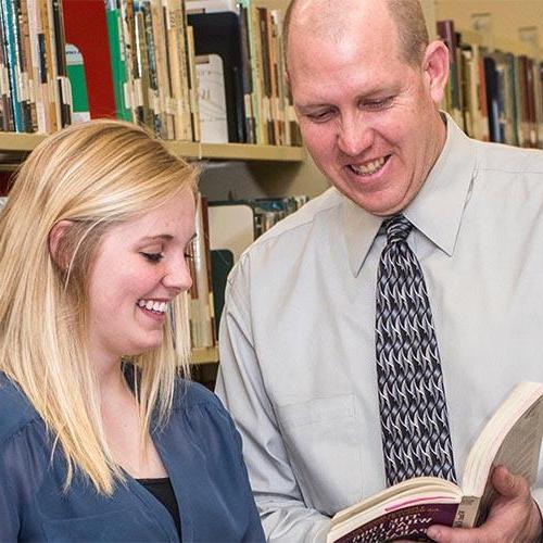 Career advisor showing a female student a book in the library.